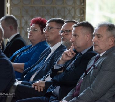 osoby siedzą na krzesłach, sluchają