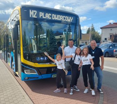 dwóch mężczyzn i dwójka dzieci pozują do zdjęcia na przodzie autobusu