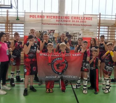 grupa osób pozuje do zdjęcia, z prozdu dwóch cłopców trzyma flagę klubu Walhalla Mińsk Mazowiecki, przewiesili na nią swoje...