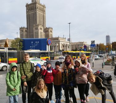 grupa dzieci ze szkoły podstawowej pozuje do zdjęcia, w tle pałac kultury i nauki/zdjęcie otwiera się w nowej karcie