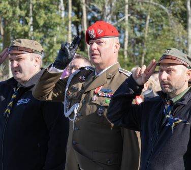 trzech mężczyzn salutuje, w tle drzewa