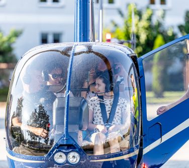 helikopter w nim osoby ze słuchawkami na uszach, przy otwartych drzwiach mężczyzna