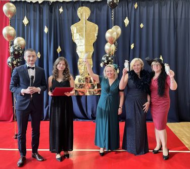 grupa osób pozuje do zdjęcia, po prawej trzy kobiety trzymają zrobione oscary, w tle duży zrobiony oscar, balony