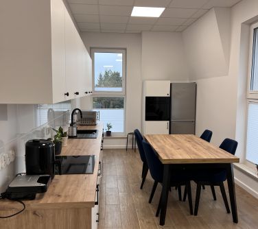 kuchnia, meble i sprzęty po prawej stół krzesłamiw z przodu lodówka
