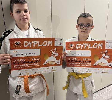 dwóch chłopców pozuje w kimonach do zdjęcia, trzymają dyplomy