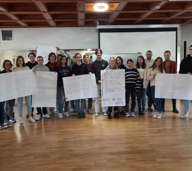 grupa osób pozuje do zdjęcia, trzymają duże, zapisane kartki