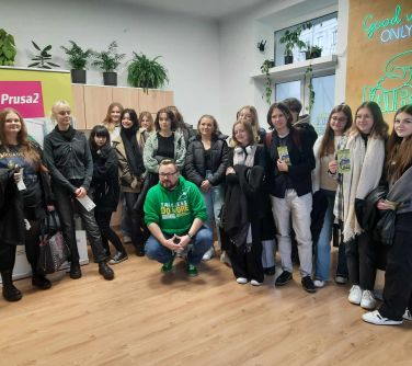 grupa osób pozuje do zdjęcia w sali , w tle okna, szafki i na nich kwiaty
