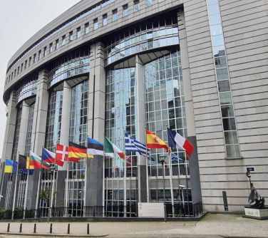 zdjęcie kolistego budynku, przed którym wywieszone są flagi różnych państw