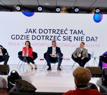 scena, na scenie pięć krzeseł na których siedzą osoby w tle baner z tytułem glównym Jak dotrzeć tam, gdzie dotrzeć się nie...