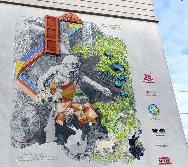 Dwór. Ściana budynku, na niej kolorowy mural