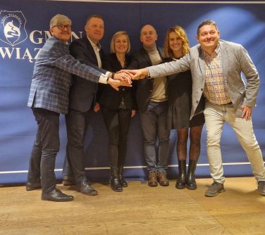 Pomieszczenie. Sześć osób łączy po środku dłonie