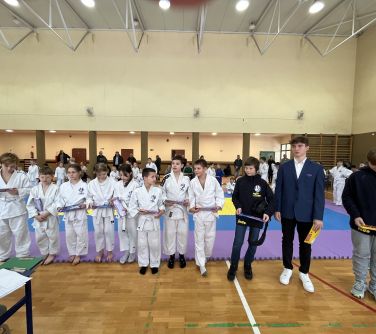Hala sportowa. Grupa dzieci w kimonach z upominkami pozuje do zdjęcia