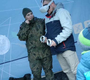 Pod namiotem kobieta żołnierz obok mężczyzna w goglach VR