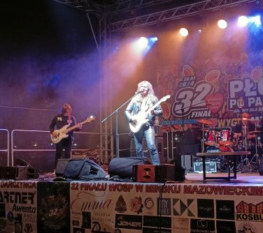 Na scenie dwóch mężczyzn gra na gitarach