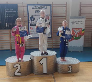 Hala sportowa. Na podium dziewczynki z medalami na szyi i dyplomami w dłoniach