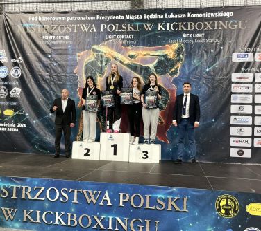 Sześć osób pozuje do zdjęcia, czworo z nich stoi na podium. Mają medale i dyplomy.