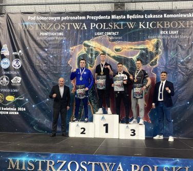 Sześć osób pozuje do zdjęcia, czworo z nich stoi na podium. Mają medale i dyplomy.