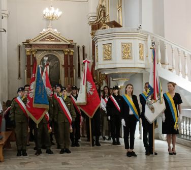Wnętrze kościoła. Po amboną przed obrazem stoją poczty sztandarowe