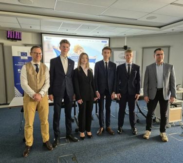 Pomieszczenie. Sześć osób pozuje przed ekranem