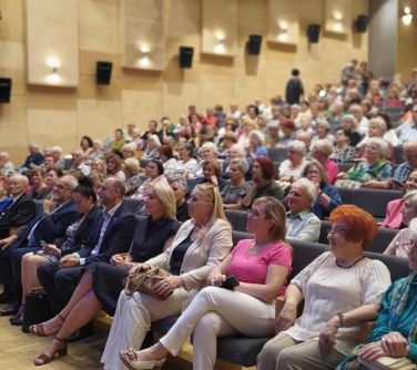 Oświetlona aula. Na fotelach siedzą słuchacze