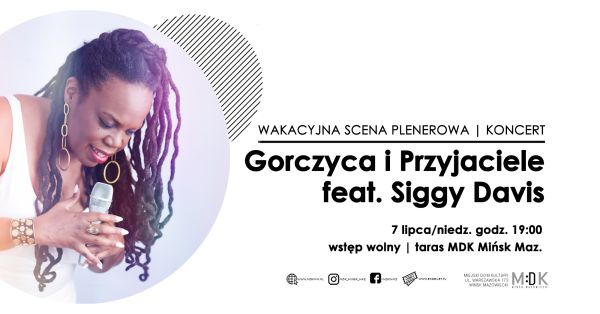Po lewej w kole kobietay ciemnej karnacji w białej sukience z mikrofoenm. Śpiewa w pozycji pochylonej. Po prawej informacje.