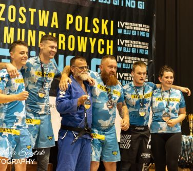 Hala sportowa. Sześć osób pozuje do zdjęcia w strojach klubowych. Na szyjach medale