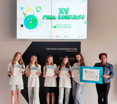 Pomieszczenie. Na tle ściany pięć nastolatek i kobieta pozują trzymając dyplomy, koieta trzyma voucher
