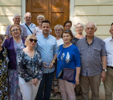 Dwór. Trzynaście osób pozuje stojąc na schodach przed kremowym domem