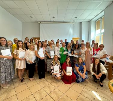 Oświetlona aula. Grupa osób pozuje do zdjęcia