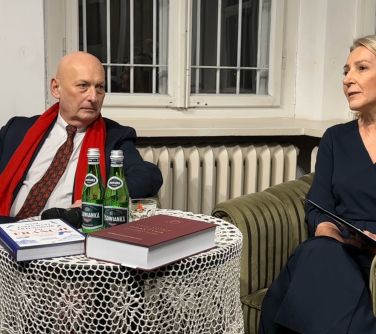 Pomieszczenie. W tle okno, noc. Na fotelach kobieta i mężczyzna. Przed nimi okrągły stół z przykryciem koronkowym...