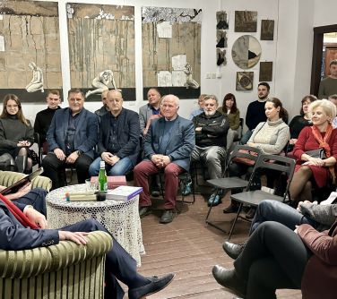 Pomieszczenie. Na krzesłach słuchacze. Przed nimi na fotelach siewdzą kobieta i mężczyzna przy okrągłym stole