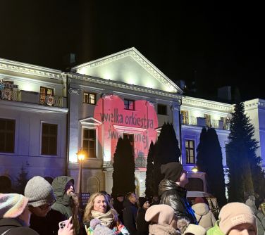 Pałac noc. Przed pałacem osoby. na pałacu wyświetlone czerwone serce z napisem wielka orkiestra świątecznej pomocy