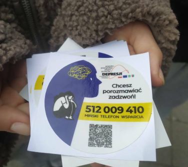Na dłoniach leżą kolorowe wlepki