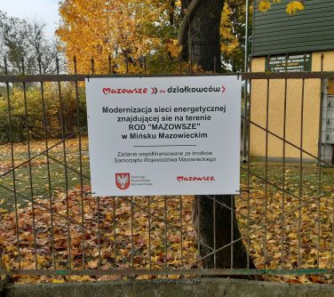 Na dworze, jesienny, pochmurny dizęń. Na ofrodzeniu tabliczka mazowsze dla działkowców