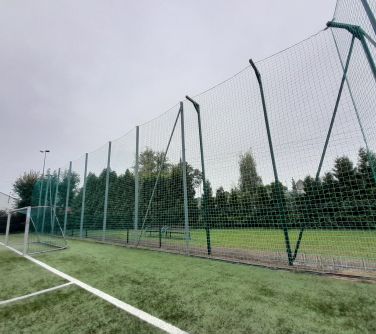 Pochmurny dzień, na zewnątrz. Boisko. na przodzie wysoka krata