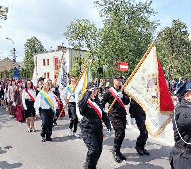 Na dworze, dzień. Po ulicy maszerują poczty sztandarowe