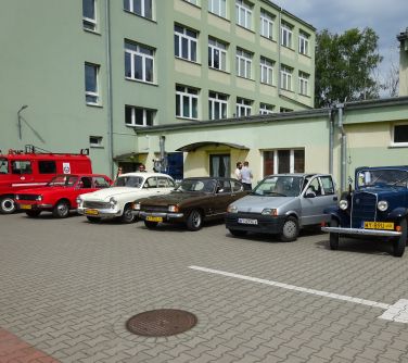 Słoneczny dzień. Sześć starych samochodów przed jasno-zielonym budynkiem
