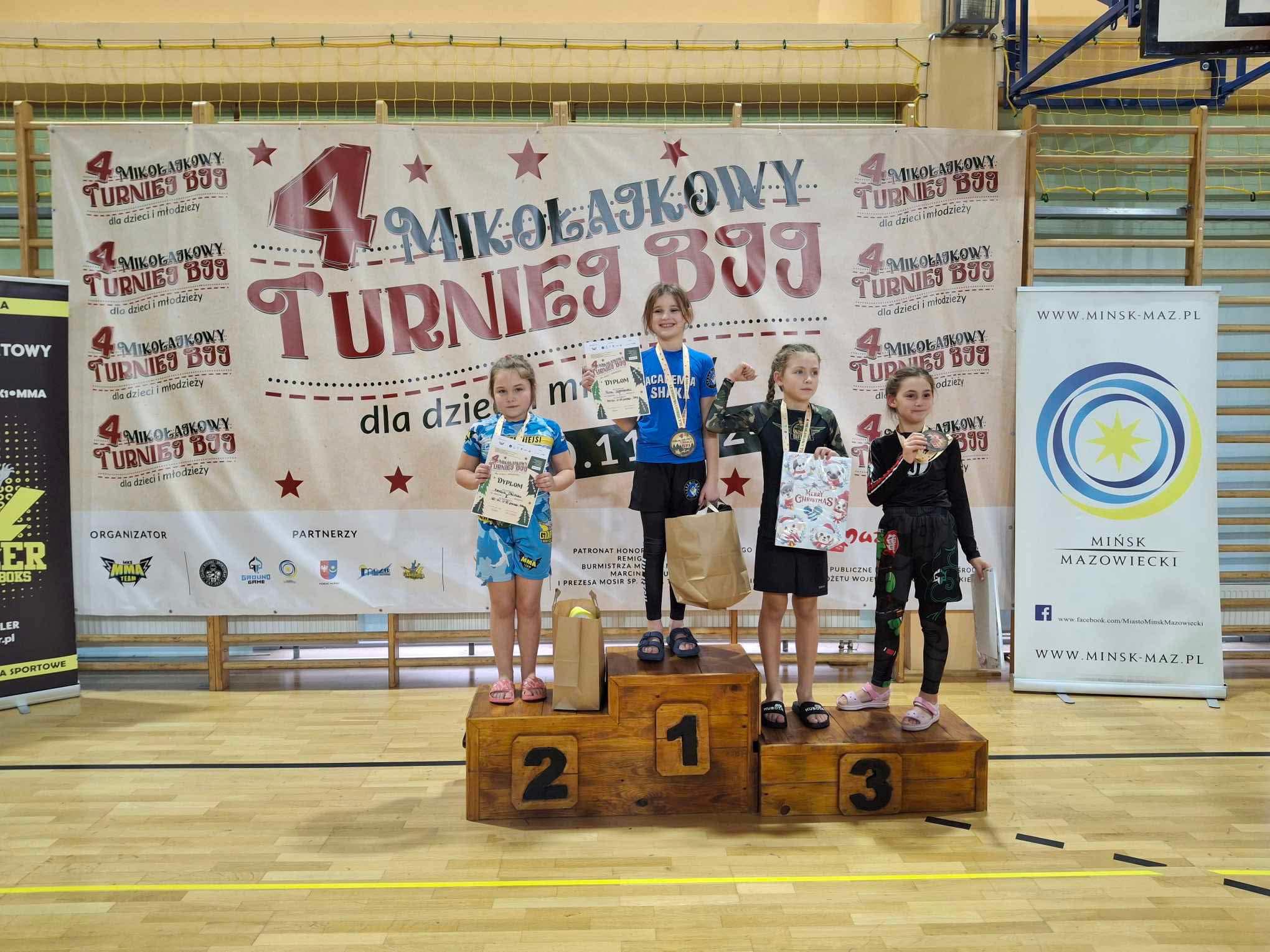 ala sportowa. Na tle dużego baneru podium. Na podium zawodnicy