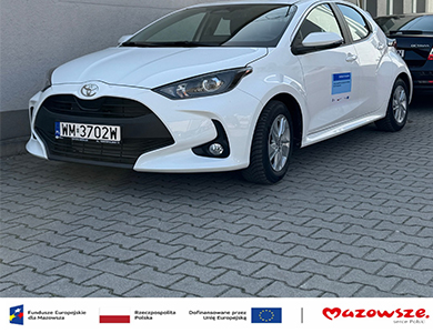 Biały samochód. Stoi przodem na kostce.