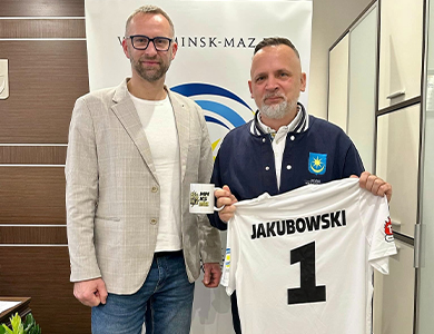 jasne pomieszczenie. Dwóch mężczyzn. Po prawj trzyma koszulkę