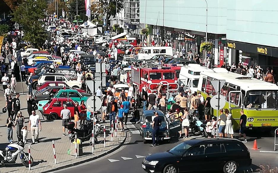 Dwór. Ulica i parkingi wypełnione zabytkowymi pojazdami i oglądającymi je osobami.